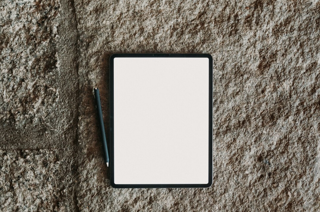Person taking notes on a tablet at a wooden desk